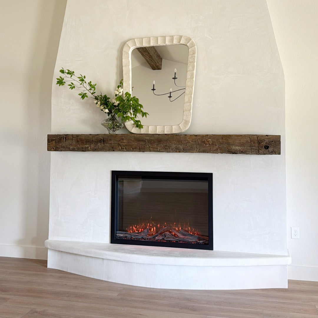Fireplace in a bump out in a unique shape and texture with a rough wood mantel.