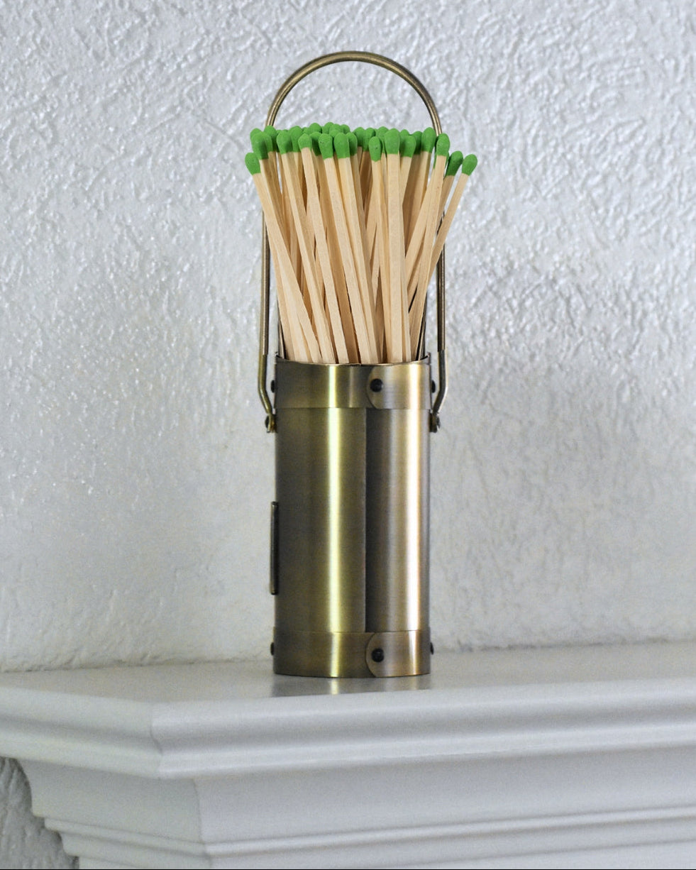 Modern Ember brass match holder canister with green-tipped long fireplace matches