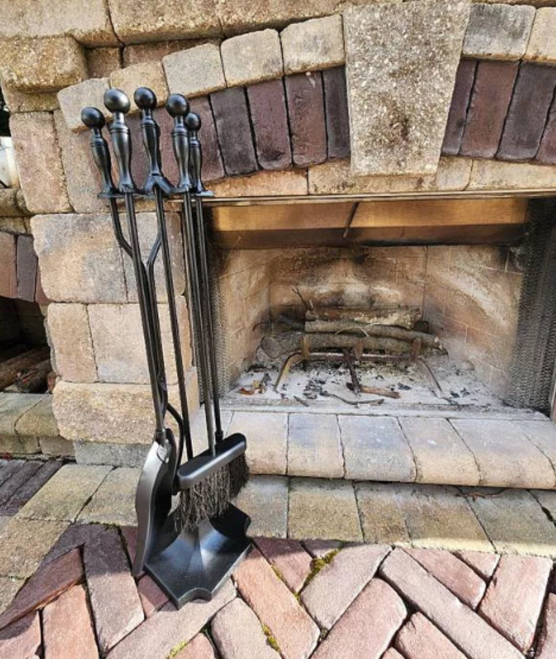 customer image of classic black fireplace tool set with brush, shovel, poker, and tongs in front of stone outdoor fireplace