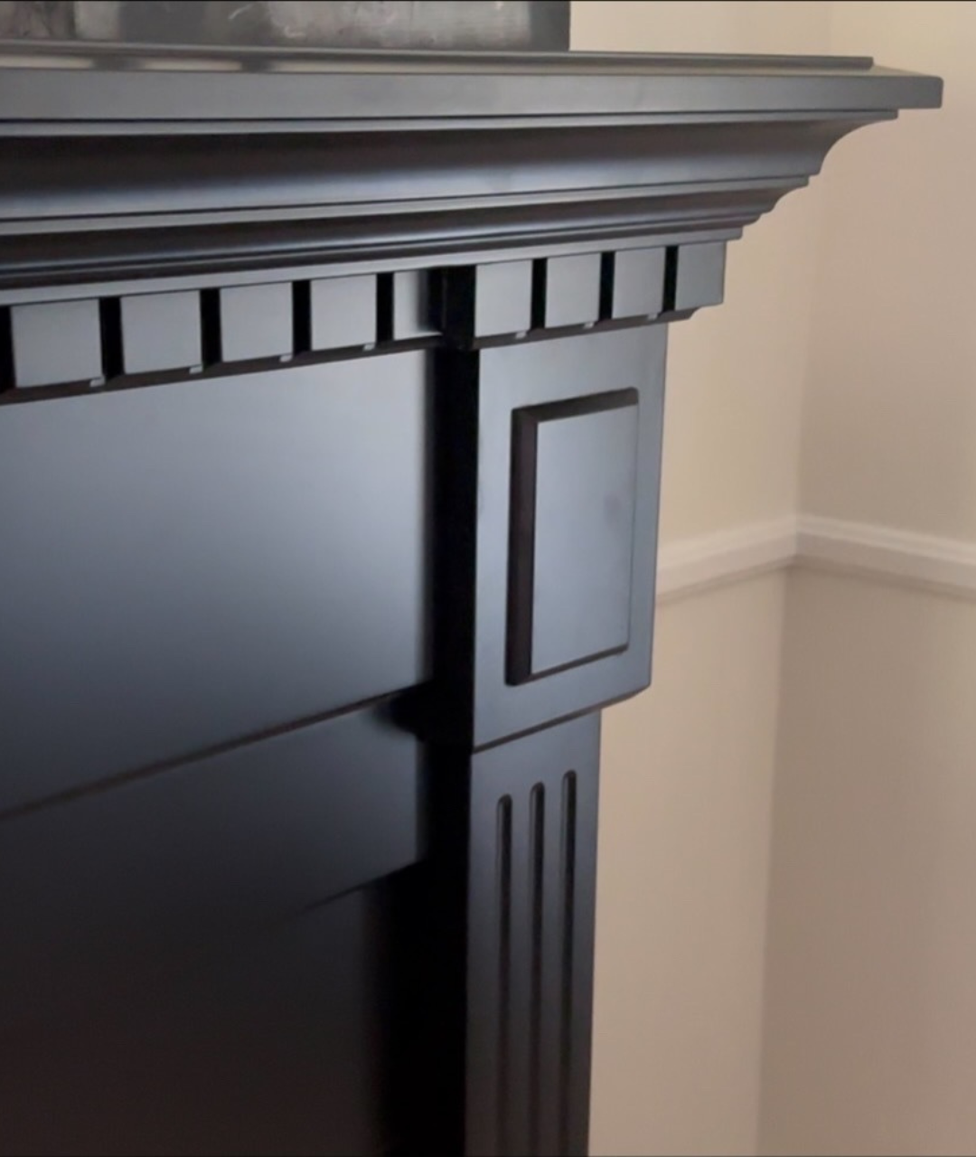Close-up of elegant black fireplace mantel with traditional molding and fluted detailing, designed by Modern Ember