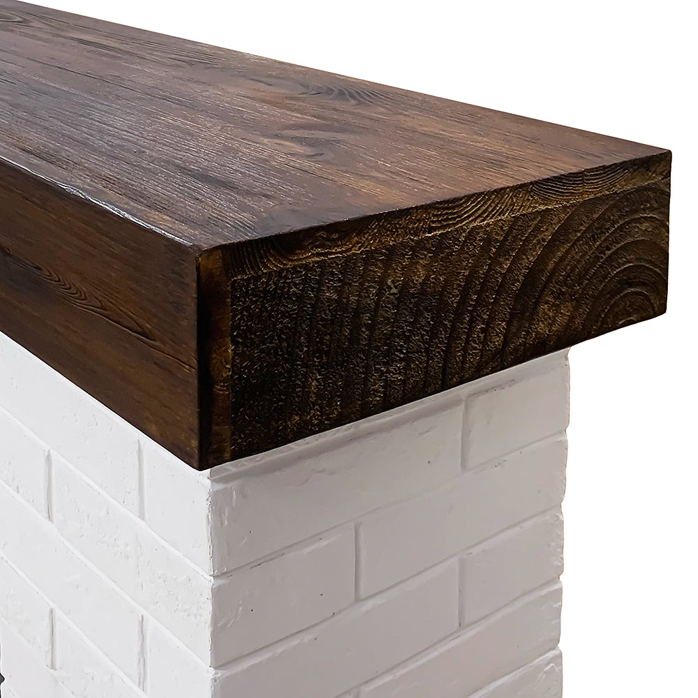 Close-up of the real wood mantel shelf top in a walnut finish, sitting atop the white faux brick surround.