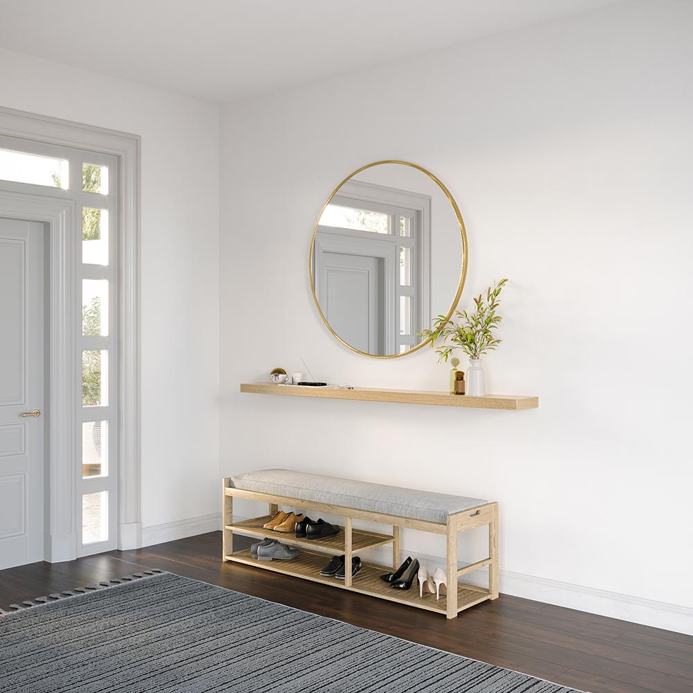 angle view of Alma Floating Wall Shelf in natural wood finish, styled in a bright entryway with a round wall mirror, books, and a vase