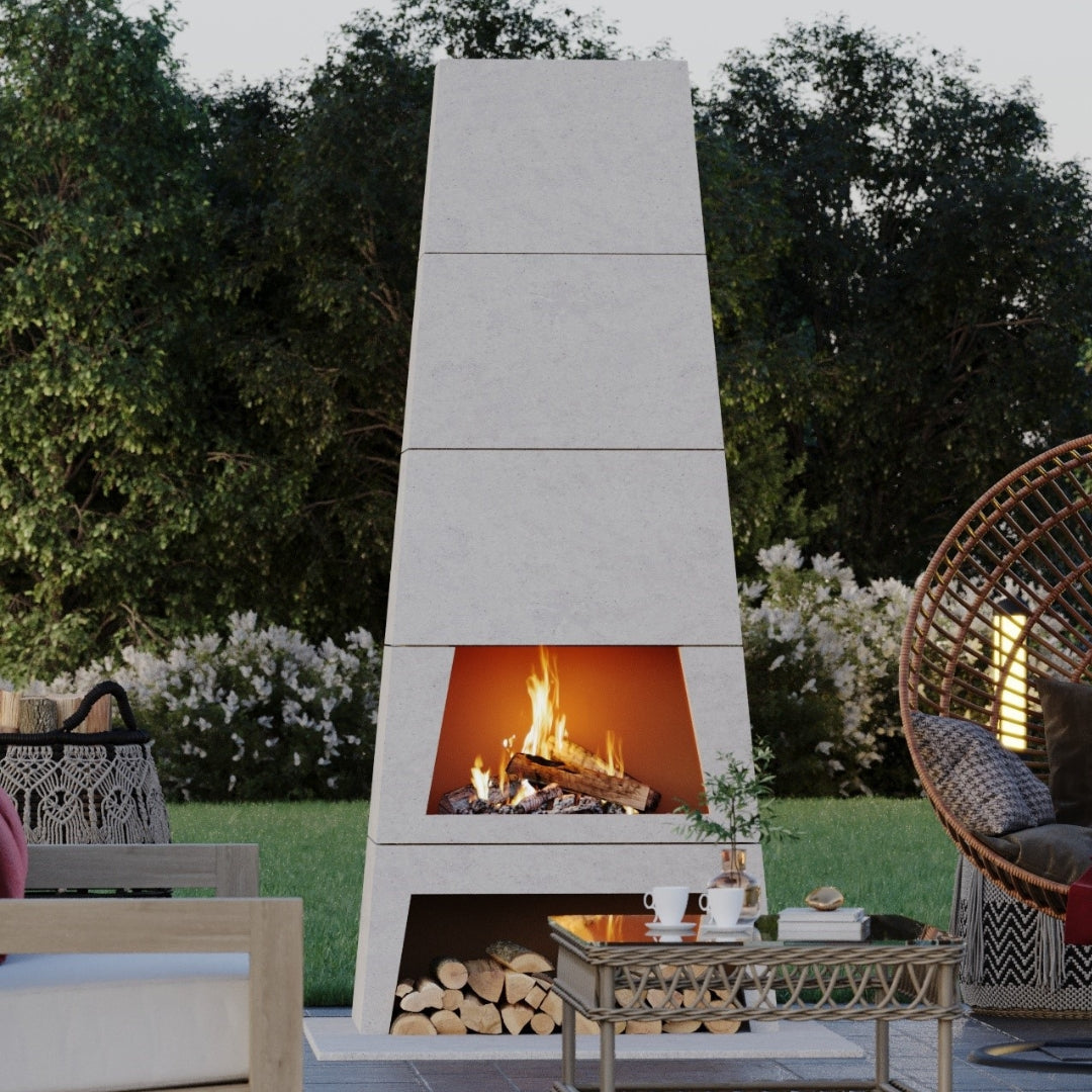 Wide shot of an outdoor entertaining space featuring the Kairo Fireplace centerpiece, demonstrating its wood-burning fire.