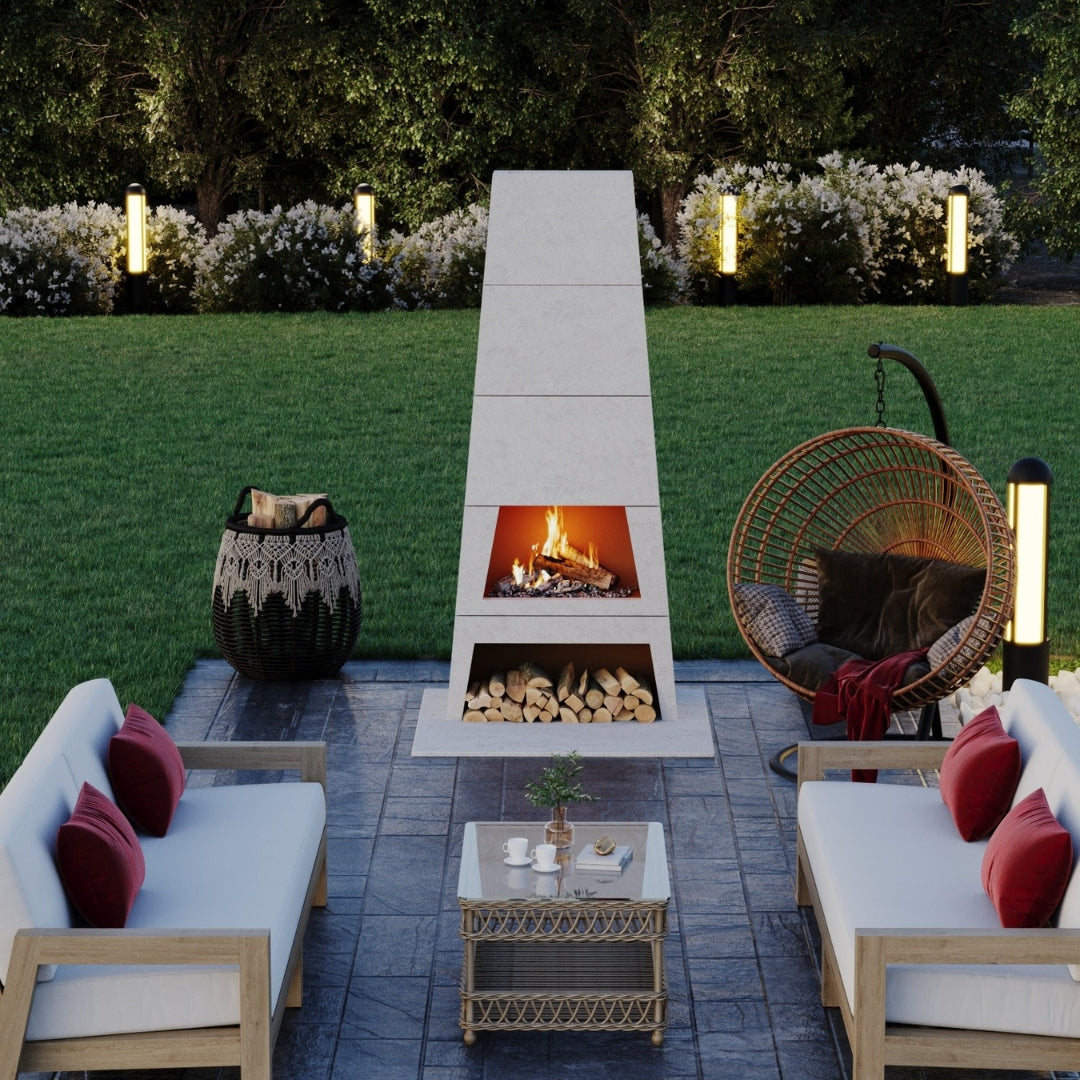 Kairo Outdoor Woodburning Fireplace glowing at dusk, providing natural warmth and year-round ambiance to an outdoor space.