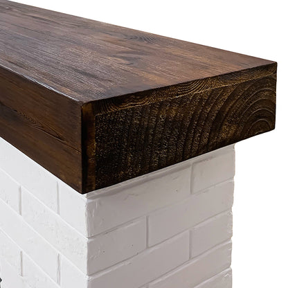 Close-up of the real wood mantel shelf top in a walnut finish, sitting atop the white faux brick surround.