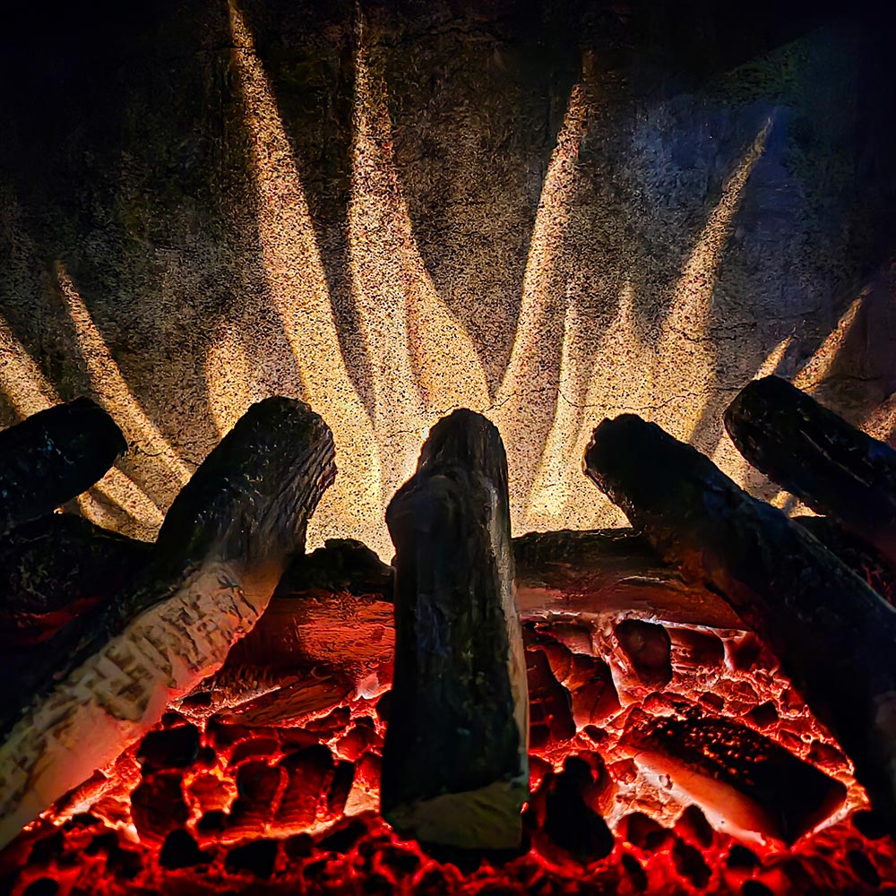 Extreme close-up of the Harlowe stove's custom flame effects, showing bright orange and yellow flames over the realistic log set.