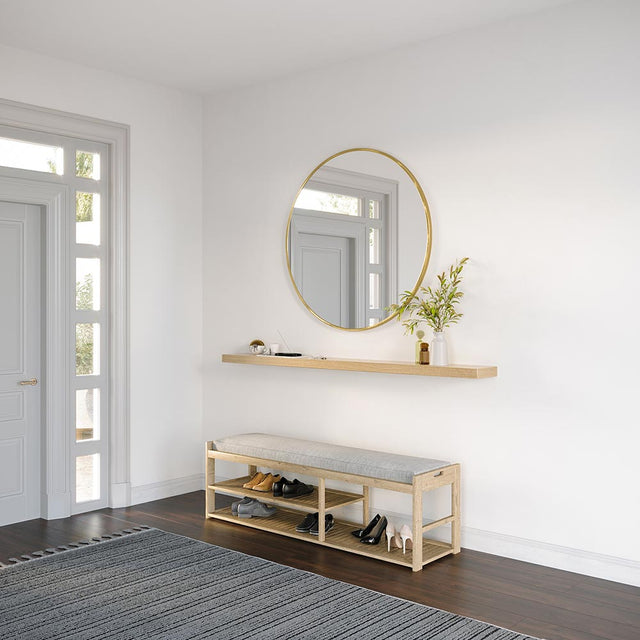 angle view of Alma Floating Wall Shelf in natural wood finish, styled in a bright entryway with a round wall mirror, books, and a vase