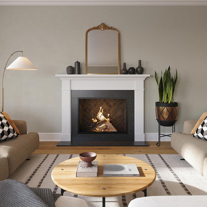 Straight on view of Arden 48x41 Wood Mantel in white painted finish, framing a herringbone firebox with a burning wood fire, styled with modern ceramic vases and a wall mirror for a transitional living room design.