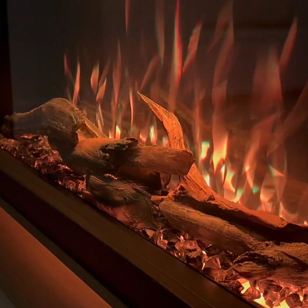 Close-up of the Highmark fireplace's log set, showing intense orange and yellow flames and the illuminated embers.