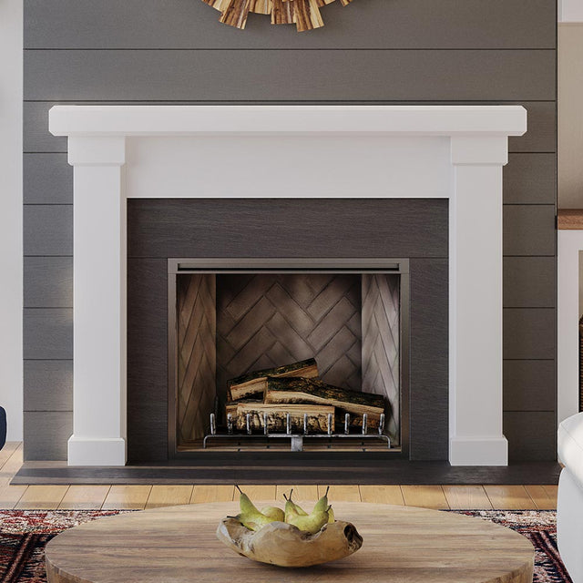 Modern Ember Nobel Mantel Surround in white finish framing black firebox with herringbone interior, styled in modern living room with wood accents.