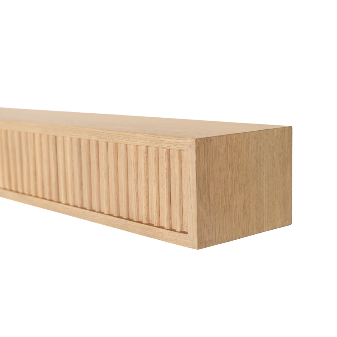 Angled view of the light wood Monti Boxframe floating mantel, detailing the white oak wood grain and fluted face.