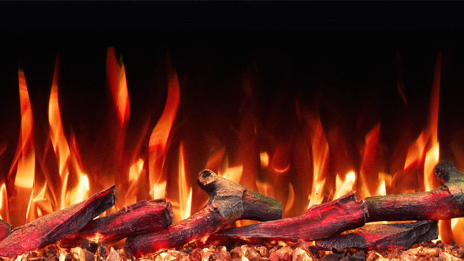 Close-up of a electric fireplace-style flame effect with glowing orange and yellow flames rising above dark red logs and embers against a black background.