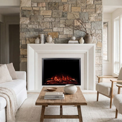 A modern electric fireplace with glowing orange and red faux logs, set within a white mantel and a rustic stone wall, in a bright, contemporary living room.